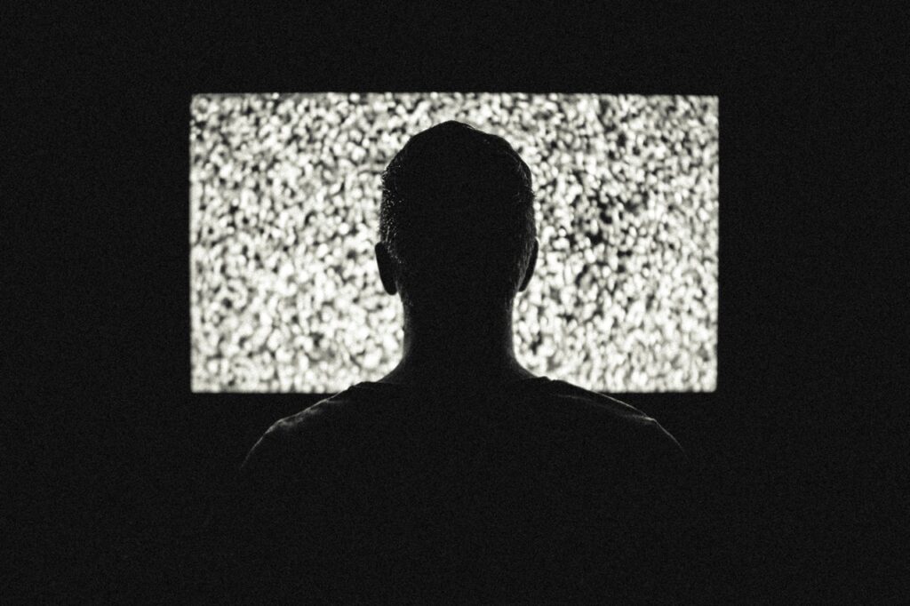 male in front of tv with static on screen