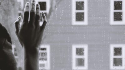 suicide teen hand on glass with rain falling down
