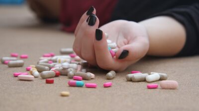 photo of girl on floor with pills in her hand