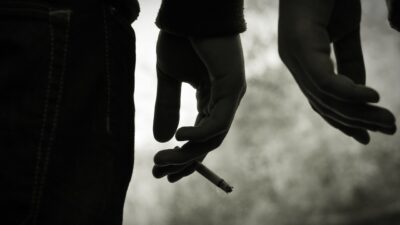 photo of teen boy holding cigarette in hand