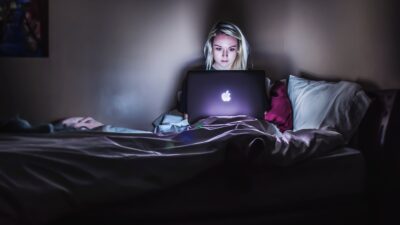 teen girl in bedroom with laptop on her bed